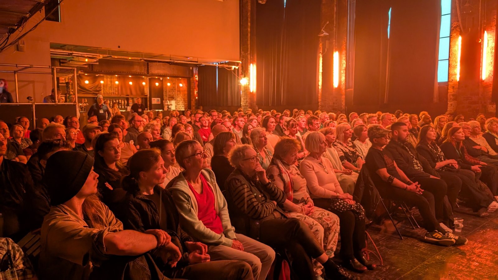 Audience of hundreds in dark room listen intently